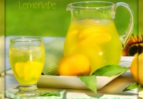 Pitcher of cool lemonade with glass on table